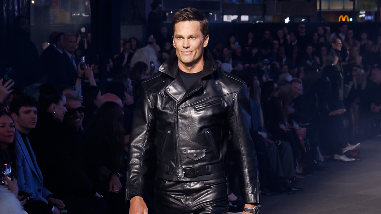 Tom Brady smirking as he walks the runway for Gucci in an all-leather outfit