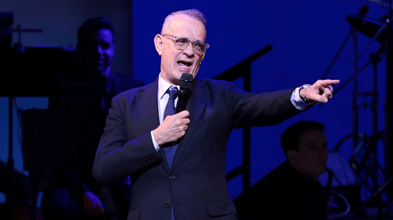 Tom Hanks on stage with microphone pointing