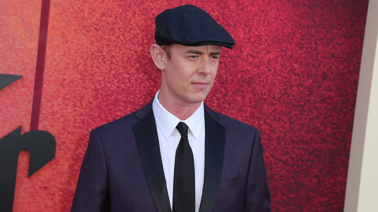 Colin Hanks wearing a cigarette hat and navy suit at "The Offer" premiere