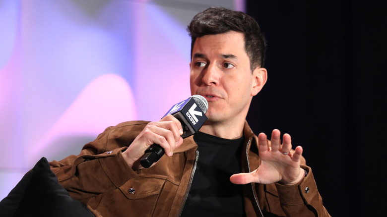 Tom Llamas wearing a black shirt and a brown jacket