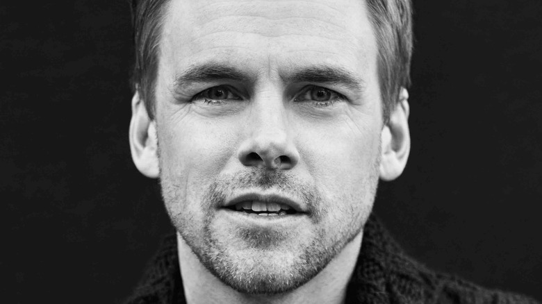 Tommy Dewey smiling in black and white