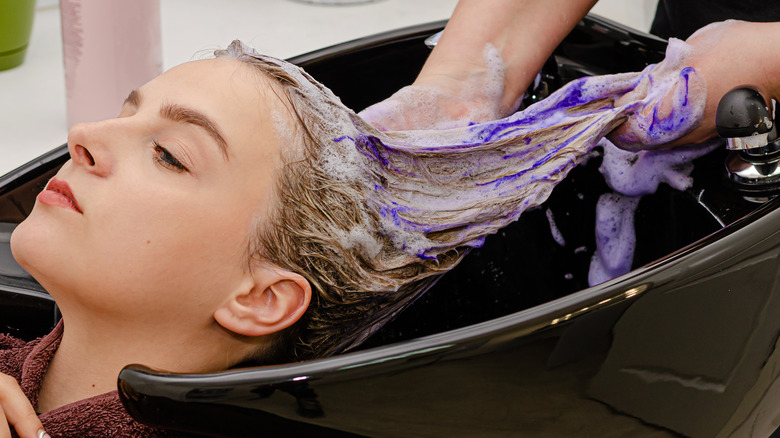 woman getting her blonde hair washed with purple shampoo