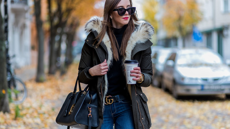 Woman in a Gucci belt, parka, and sunglasses