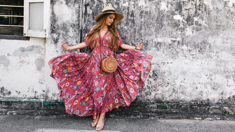 Woman in maxi dress in front of a gray wall