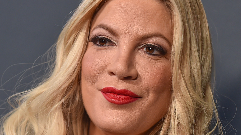 Tori Spelling posing with a close-lipped smile