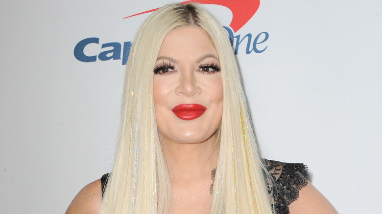 Tori Spelling in front of white backdrop