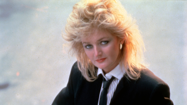 Bonnie Tyler wearing a black suit and tie and looking serious in her younger years.