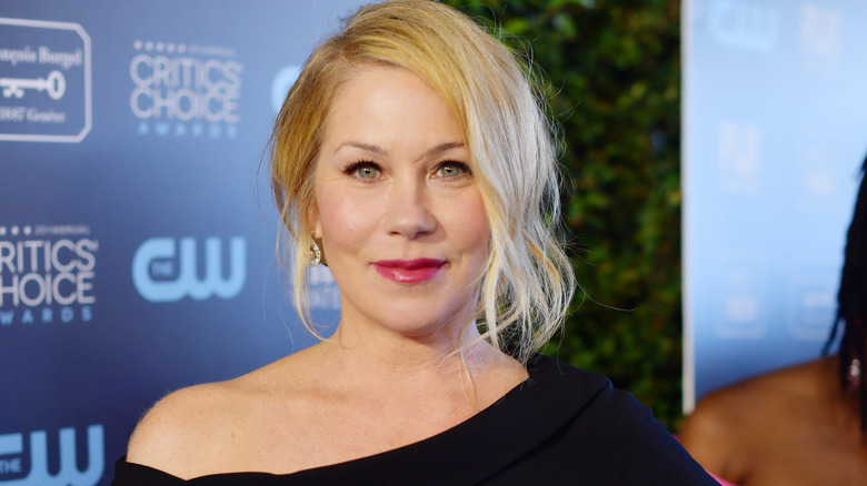 Christina Applegate smiling while posing in a black off the shoulder dress