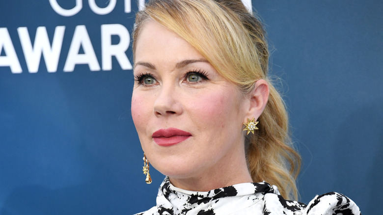 Christina Applegate smiling while posing at an event in a monochrome patterned dress