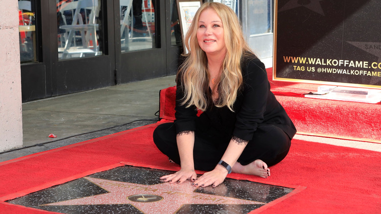 Christina Applegate smiling while posing barefoot with her star on the Hollywood Walk of Fame