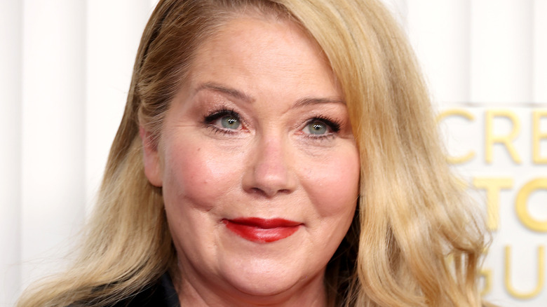 Christina Applegate smiling while posing at an event in a black outfit