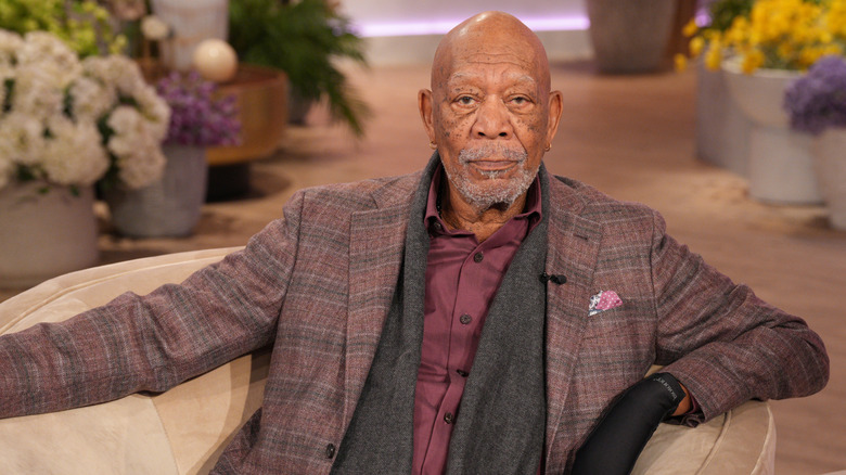 Morgan Freeman in a plaid jacket and black glove on left hand