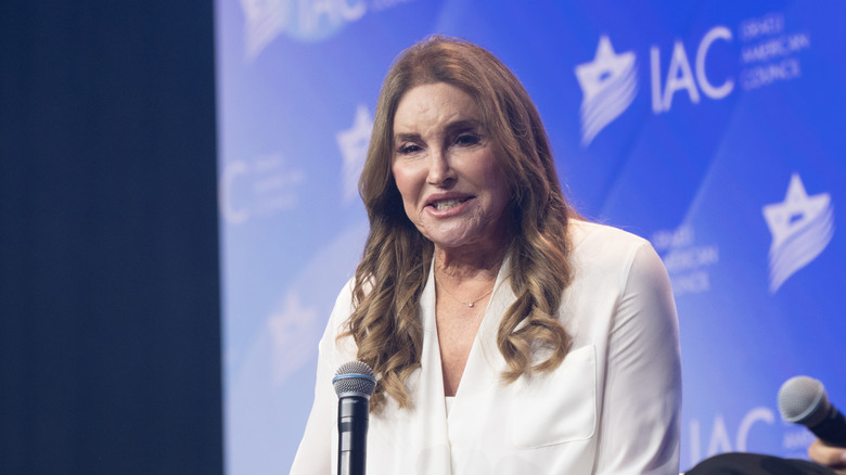 Caitlyn Jenner speaking on a mic wearing white ensemble