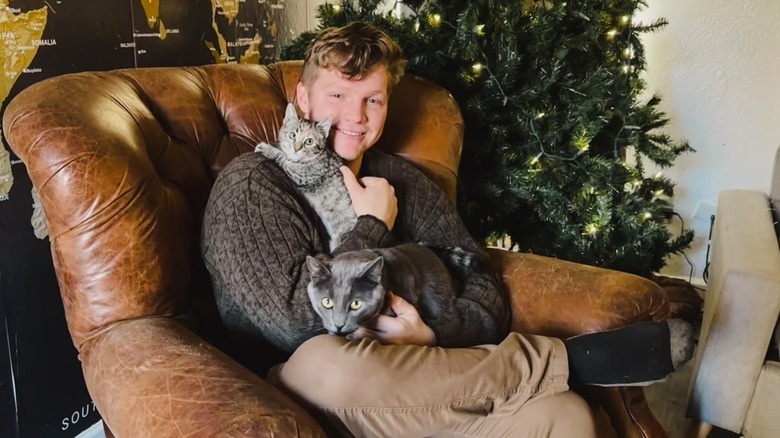 Garrison Brown smiling, holding cats