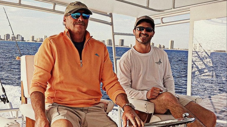 Alan Jackson in orange shirt, ball cap, and sunglasses on a boat with son-in-law Ben Selecman