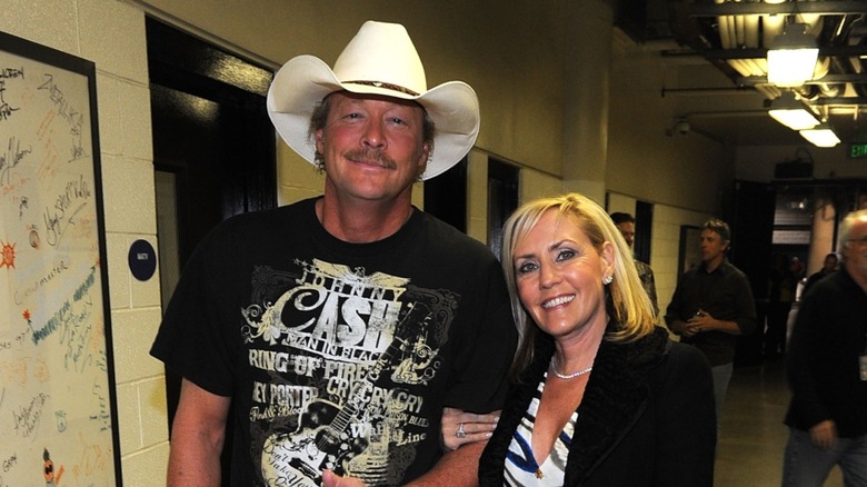 Alan Jackson in black Johnny Cash shirt and cowboy hat and wife Denise in black and white zebra top and black blazer