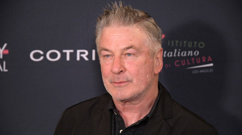 Alec Baldwin in front of dark backdrop