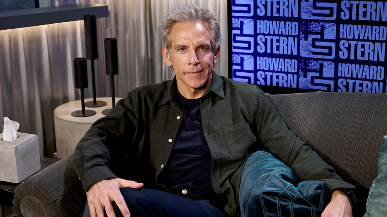 Ben Stiller posing for photos in a grey shirt while sitting on a sofa