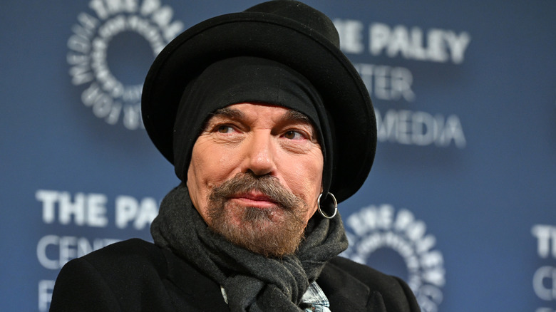 A closeup of Billy Bob Thornton listening to a question in a black hat and matching headscarf