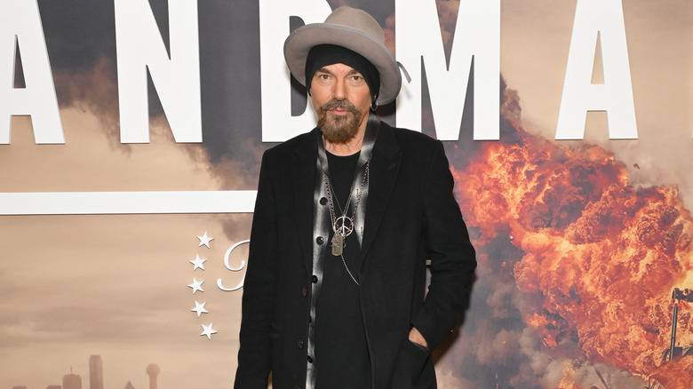 Billy Bob Thornton posing in a black jacket and a big hat at a Landman event