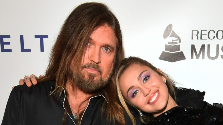 Miley Cyrus with head on Billy Ray Cyrus' shoulder