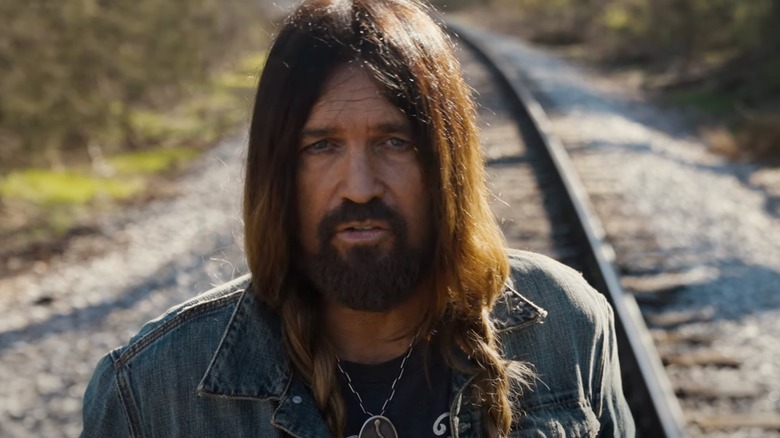 Close up of Billy Ray Cyrus with braided hair on railroad track