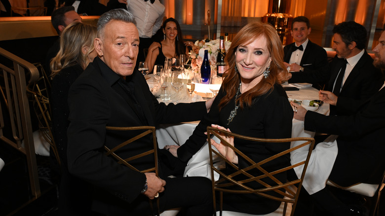 Bruce Springsteen Patti Scialfa seated at a table together as they smile for the camera