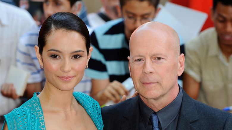 Emma Heming wearing a blue dress next to Bruce Willis who's wearing a black suit at the "Red 2" premiere.