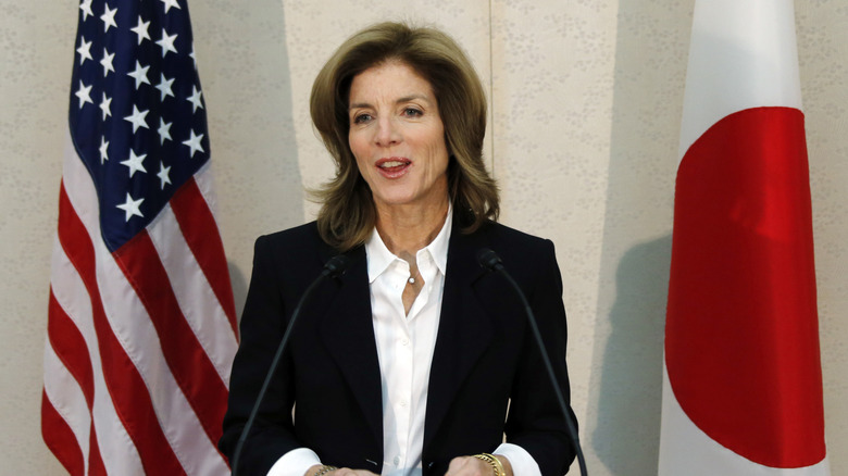 Caroline Kennedy posing between American and Japanese flags