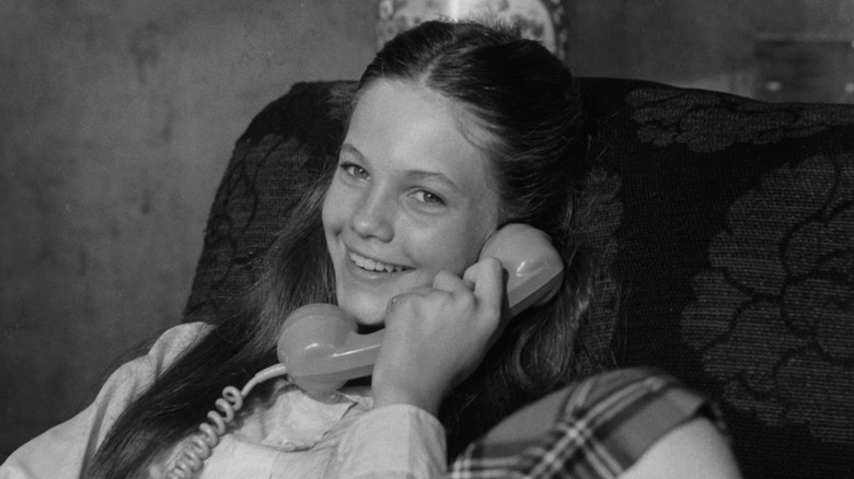 A young Diane Lane smiling and holding a phone