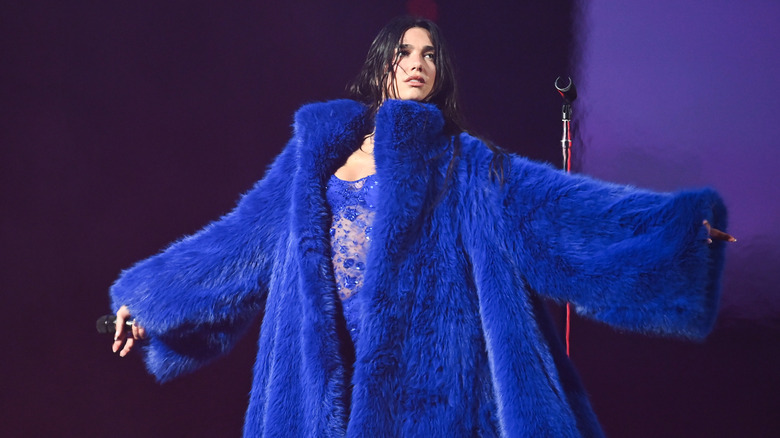 Dua Lipa wearing a blue coat on stage during her tour