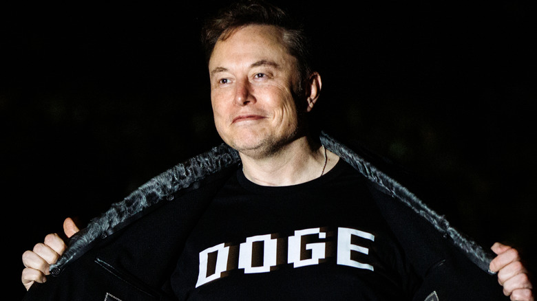 Elon Musk flashing his DOGE shirt and smiling