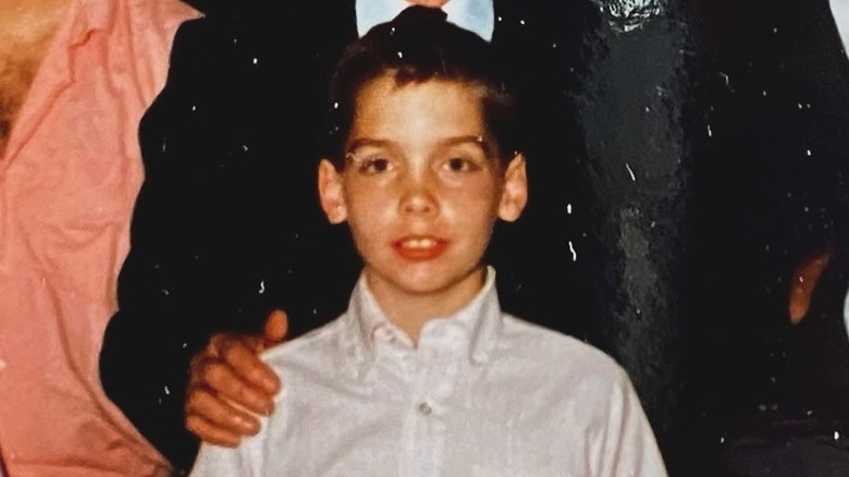A young Clint Harp posing in a white button-front shirt