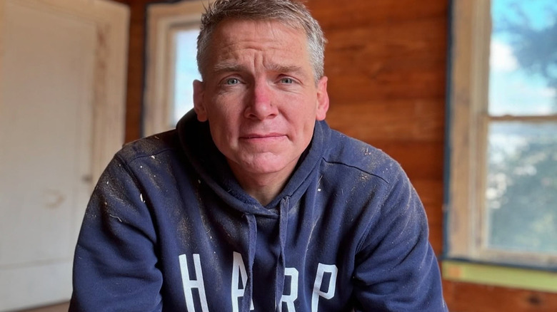 Clint Harp covered in paint sitting in a home he's working on.