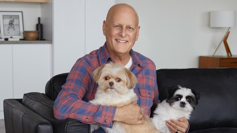Dave Coulier poses without any hair while holding two dogs