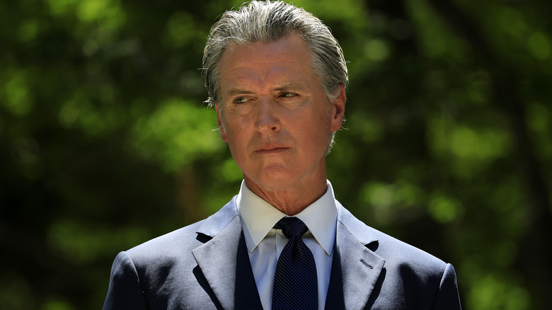Gavin Newsom wearing a somber expression in a dark suit