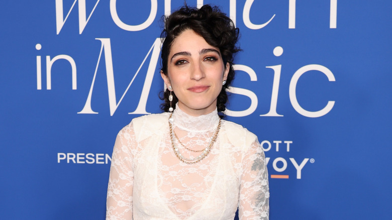 Emily Estefan posing for photos in a white lace bodysuit