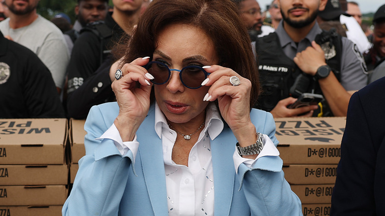 Jeanine Pirro putting on her sunglasses in a light blue blazer and white blouse