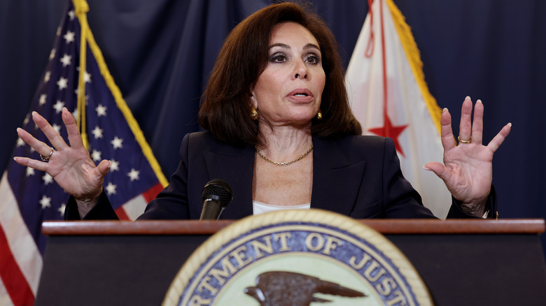 Jeanine Pirro delivering a speech at a podium in a black blazer