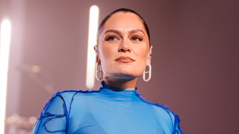 Jessie J wearing a high-necked blue outfit and sparkly earrings