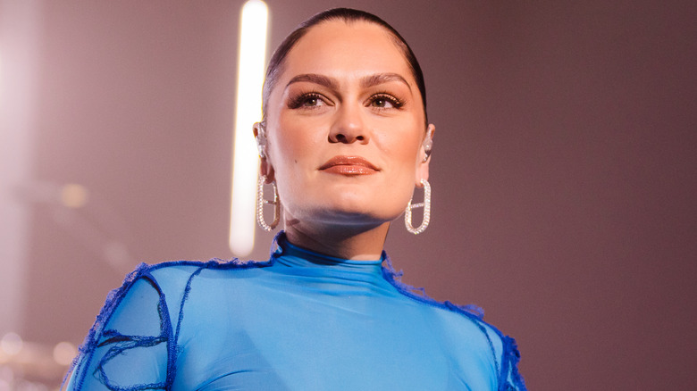 Jessie J wearing a high-necked blue outfit and sparkly earrings