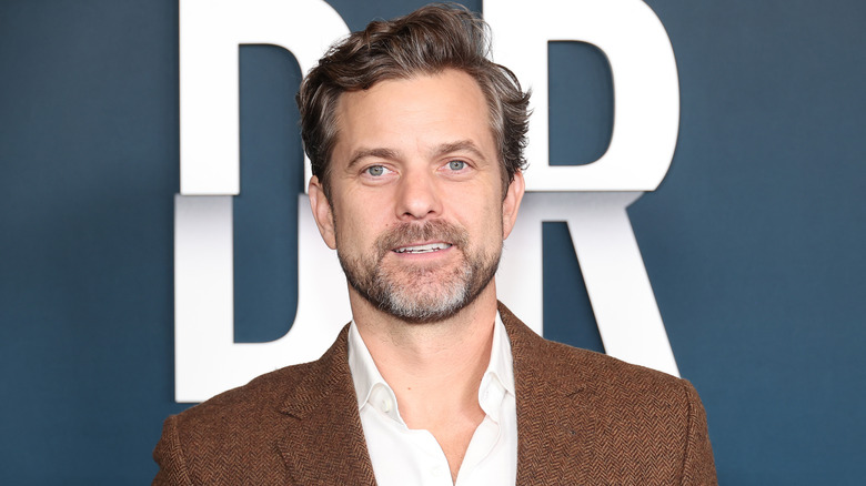 Joshua Jackson posing for photos in a brown suit jacket and a white shirt