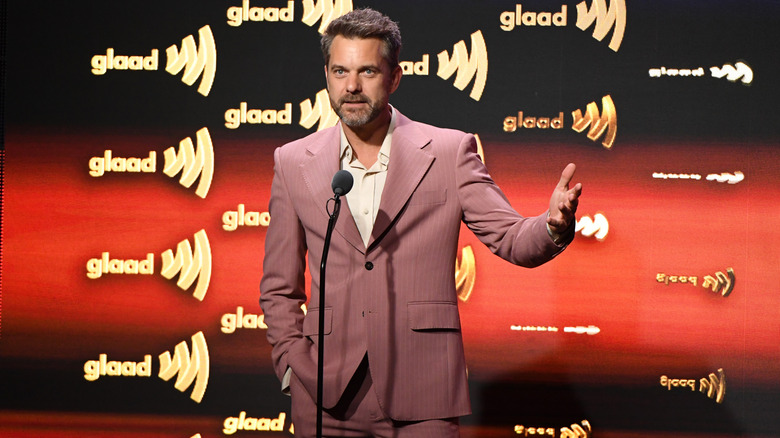 Joshua Jackson giving a speech in a purple suit while gesturing