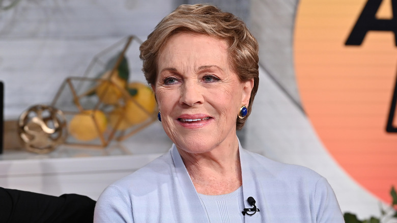 Julie Andrews smiling in a light purple outfit
