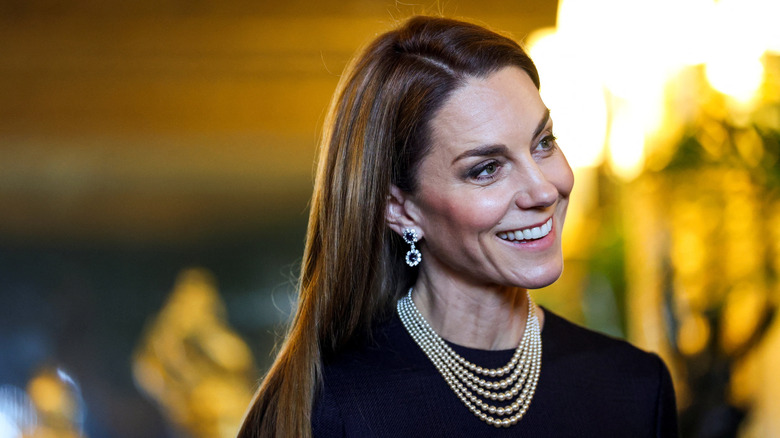 Princess Catherine smiling with her hair down in a black top with sparkly jewelry
