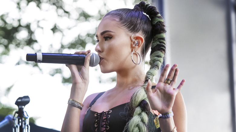 Madison Beer wearing a green braid while singing on stage in 2018