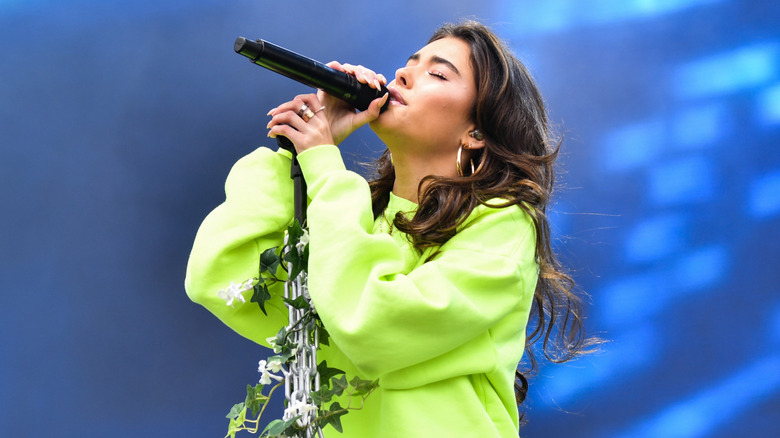 Madison Beer singing on stage in a lime green sweatshirt