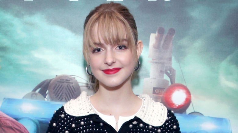 Mckenna Grace smiling in front of 'Ghostbusters' backdrop