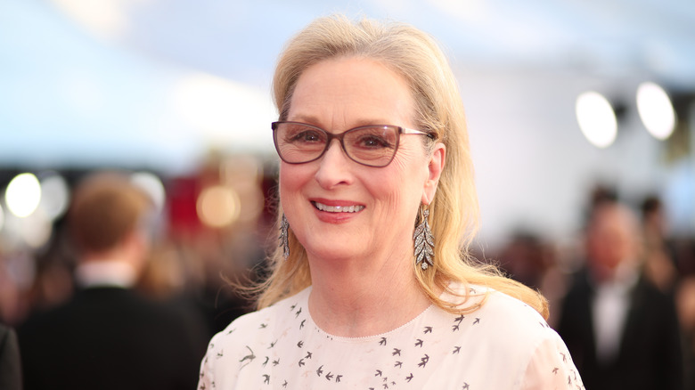 Meryl Streep smiling in a white outfit with bird prints