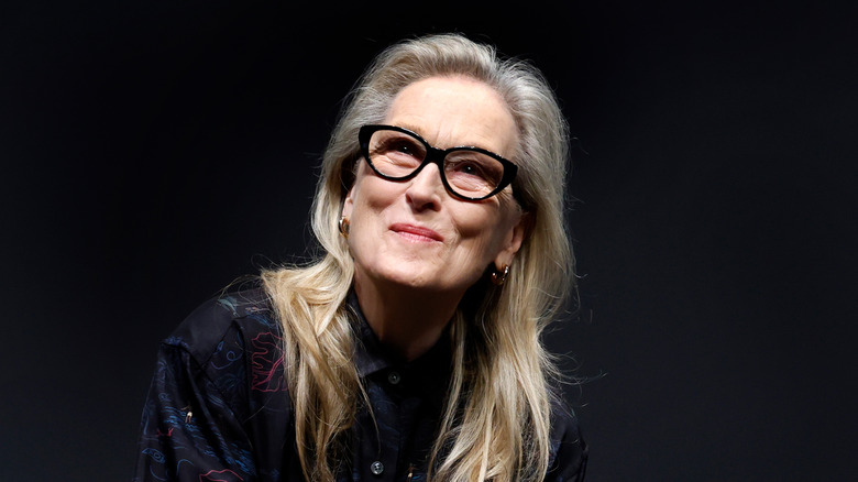 Meryl Streep in glasses against a dark background